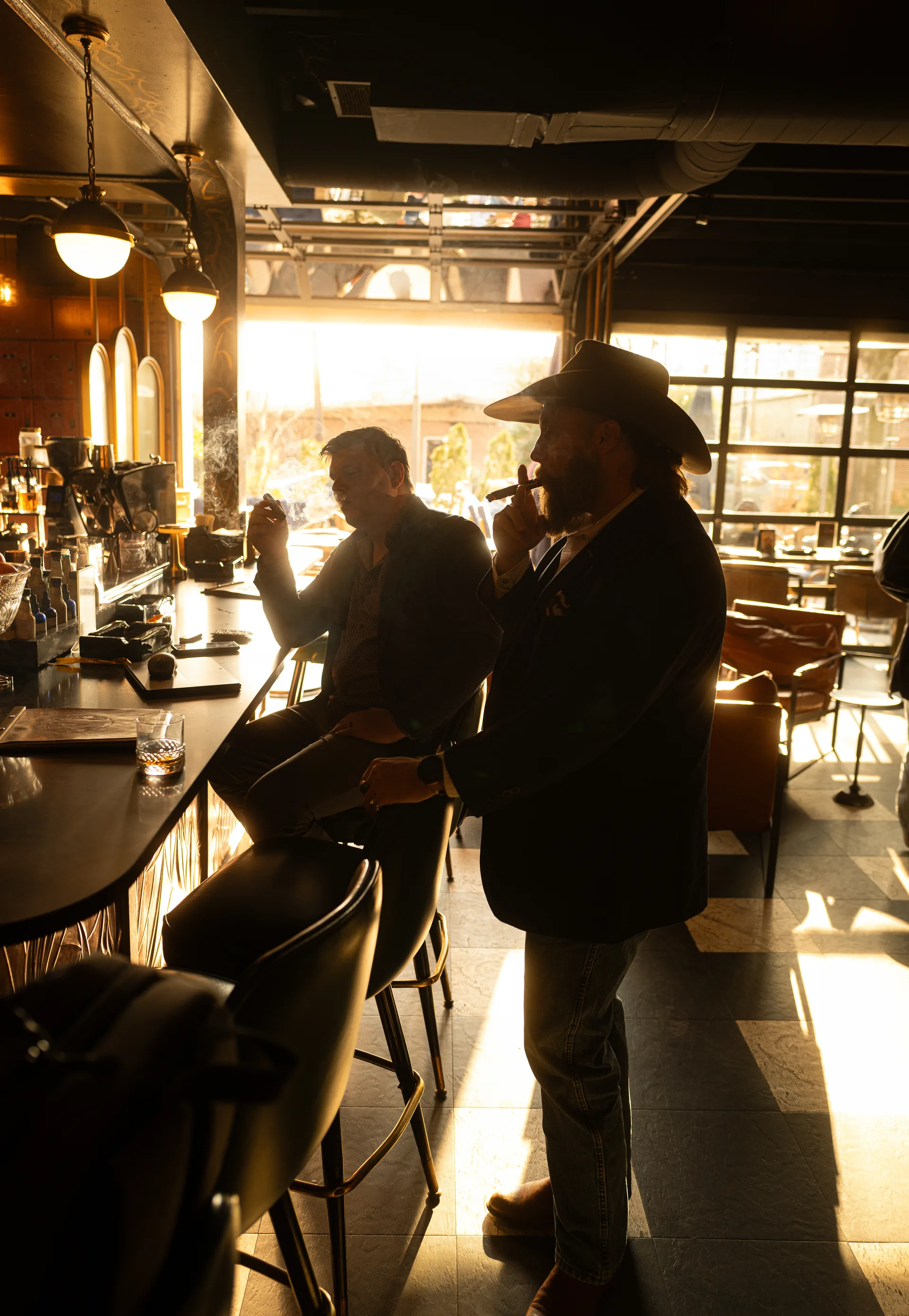 Two guests enjoying cigars at The Vintage bar in warm afternoon light