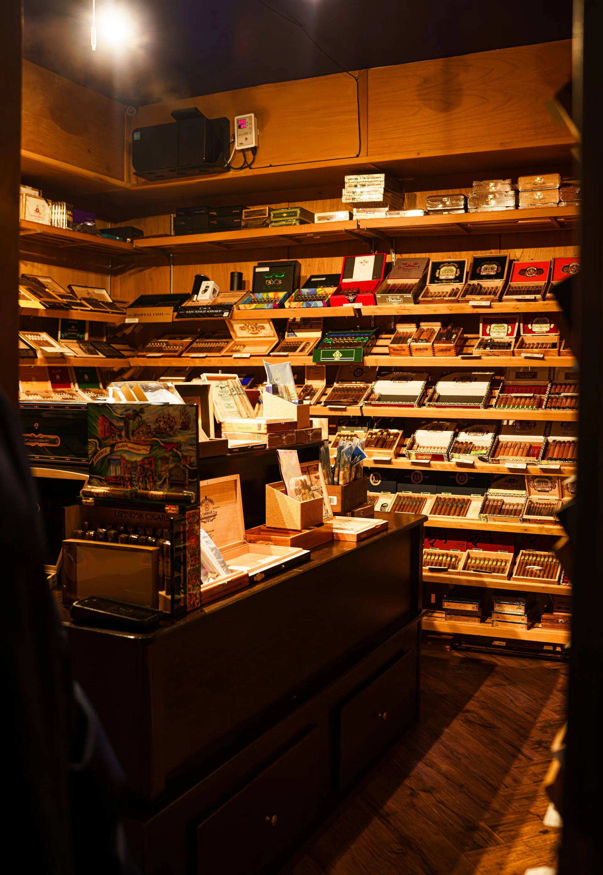 Cedar shelves filled with cigar boxes inside The Vintage walk-in humidor
