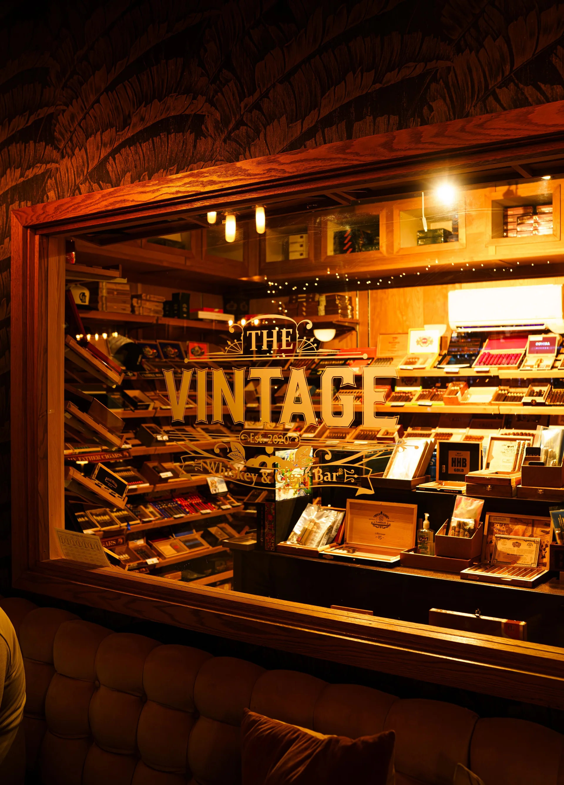 The Vintage logo on the glass of the warmly lit walk-in humidor
