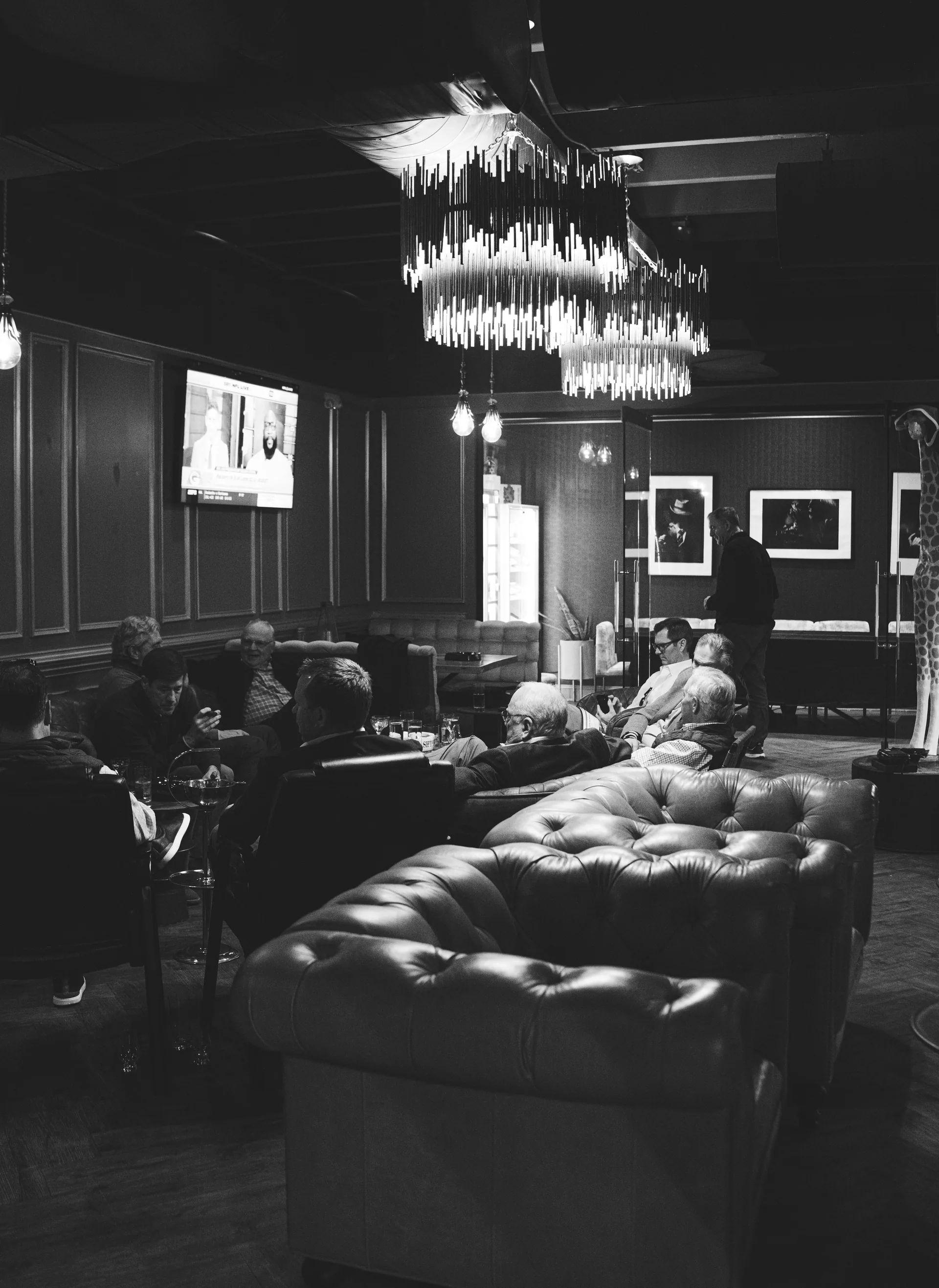 A black-and-white photograph of guests gathered in The Vintage leather lounge